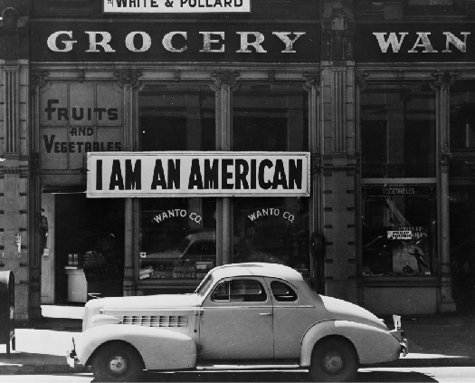 A photo of sign in a store front that says “I am an American.”